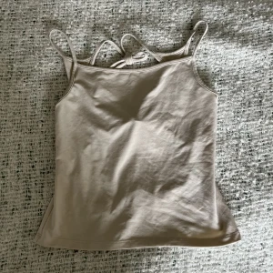 Topp med öppen rygg  - Cool beige/cremefärgad topp från weekday med öppen rygg, plus knytdetaljer i ryggen. Storlek xs!