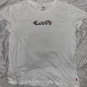 Vit ”Levis” T-Shirt - Vit Levis Tischa. Storlek S. Knappt använd, inga märken/hål/smuts men färgen på texten har försvunnit lite med tvätten, annars är kvaliten väldigt bra. Kunden betalar frakten 😚.