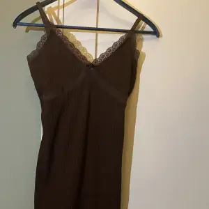 En brun klänning från h&m med spetsdetaljer. Storlek M