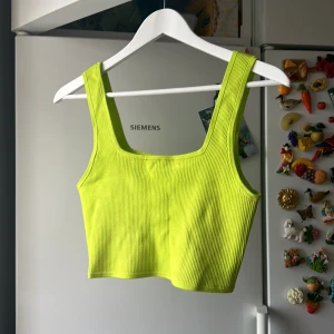 Limegrön kort topp  - Härlig grönt linne från Hm med ribbade detaljer och rakt skuren halsringning   Mycket stretch och helt oanvänd 