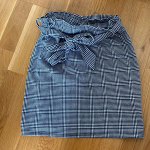 Rutig minikjol - Använt fåtal gånger. Mjuk och knyts som man önskar i midjan. Storlek 6 UK = 36 EU.