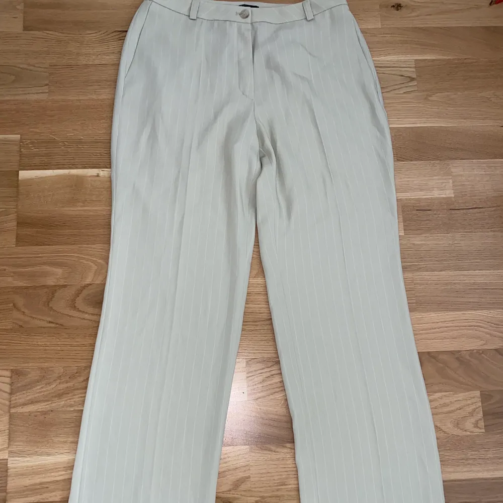 Sköna luftiga byxor i beiget tyg med vita ränder. Tighta upptill och lösa längre ner. Perfekt till sommaren . Jeans & Byxor.