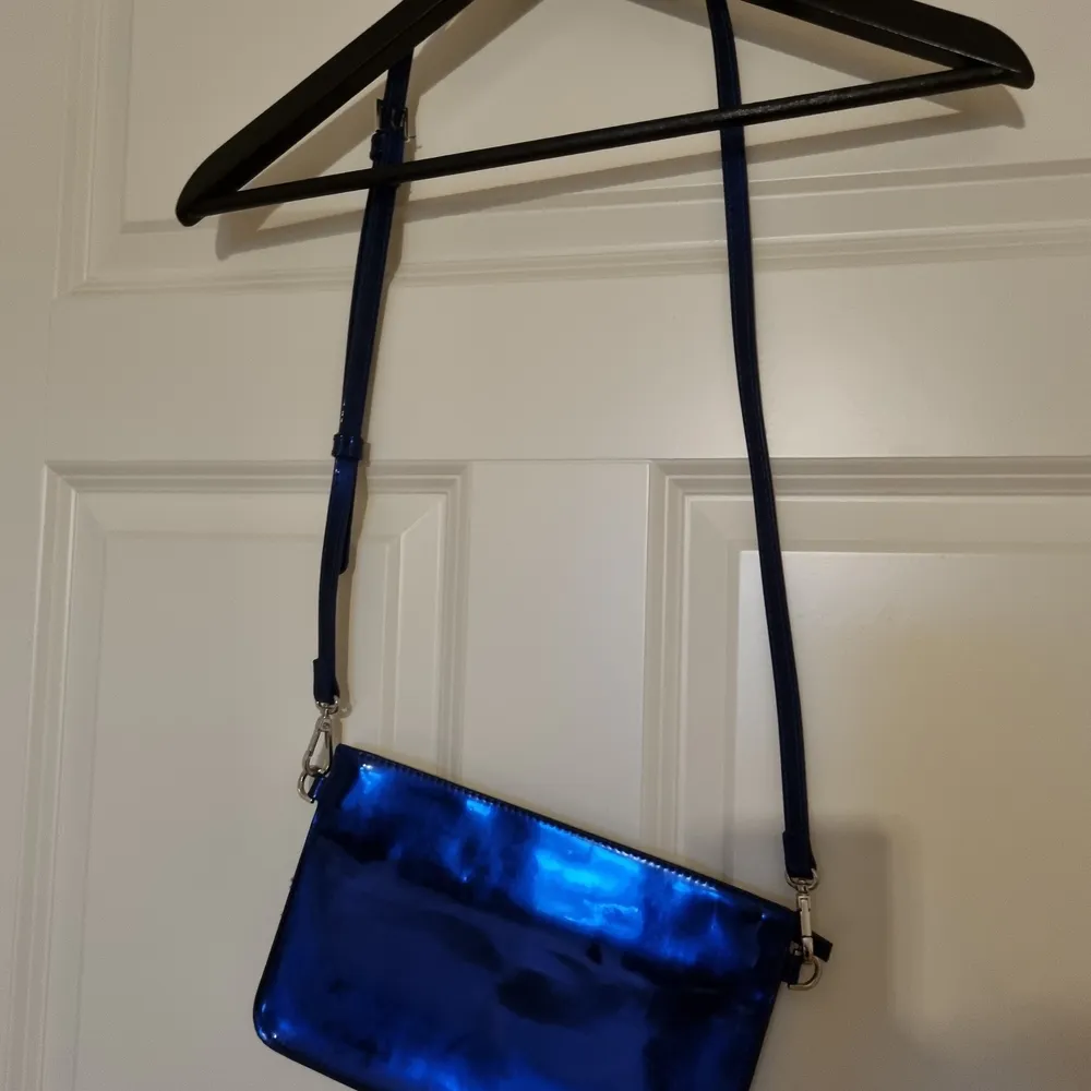 Liten blåmetallic väska från Carin Wester. Man får plats med mobil, nycklar och ett läppstift 😊. Väskor.