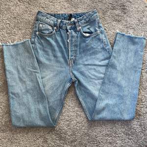 Ett par blåa högmidjade jeans med avklippta benslut osm är köpta på H&M, säljer då de tyvärr är för små! De är i storlek 32 (kontakta för exakta mått).  