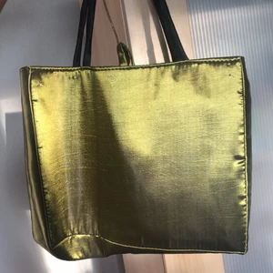 Grön satinväska - Ganska rymlig grön väska i satinmaterial. Vackert mönster på ena sidan. Ungefär storleken av en laptop. 