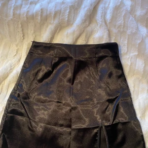 Svart oanvänd satinkjol - Helt oanvänd med liten slits, säljer även en likadan beige 50kr per st eller 80 för båda, bud går även
