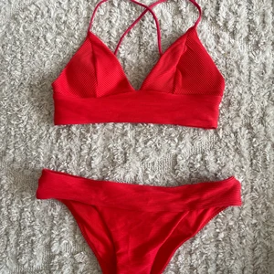 Röd bikini - Röd bikini med lite mer ”bralette”-överdel som är korsad i ryggen, bikinitrosor med en liten bredare kant vilken är en fin detalj. Superfin!!!