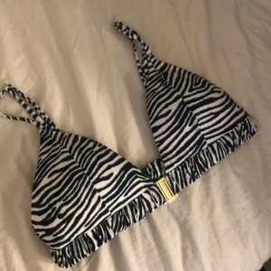 Bikiniöverdel  - Blå mönstrad bikiniöverdel från HM i storlek 38 men är som en 36/S. Endast använd 1 gång. Den har reglerbara axelband och man knäpper  den i fram. Pris 50kr + frakt