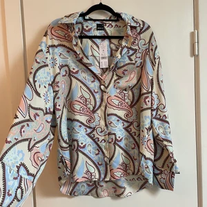 Mönstrad skjorta Gina  - Oanvänd mönstrad skjorta från Gina. Har även byxorna som matchar om någon är intresserad. Storlek 36 men oversize. Frakt tillkommer