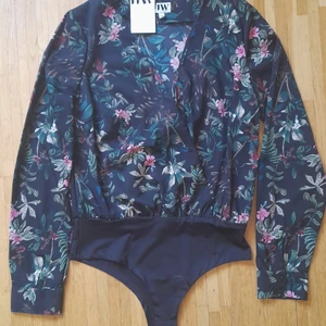 Blus - Blommig body/blus. Tyvärr för stor qå aldrig använd. 