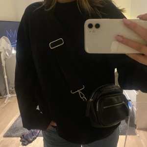 Carin Wester väska - Svart väska med ett tjockt band som går att justera.