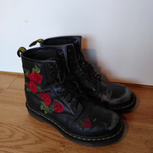 Dr Martens storlek 38 (UK 5) - Bättre begagnat. Svarta Dr Martens skor med röda rosor på sidorna. Svarta snören. Storlek 38 UK 5, gjorda i läder.