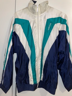 adidas jacka size M - Adidas jacka grön blå vit storlek M. Inte så använd köpt secondhand för 250kr. Bra skick. Normal fit. 
