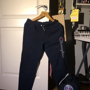 Blåa Champion Mjukisbyxor strlk 15/16 år - Fina byxor som nästan aldrig komm till användning, därav säljer jag den. Tyvärr har den en bleknings fläck (bild 3) som jag ej testat att ta bort. Strlk: 15/16år = S/xs herr