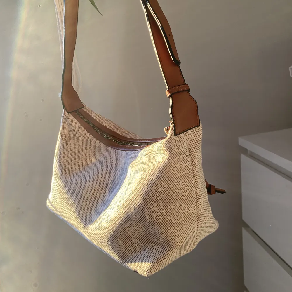 Snygg rymlig baguetteväska med fint beige/vitt mönster och bruna detaljer. Justerbart band för att kunna bestämma längden på väskan 🤍. Väskor.