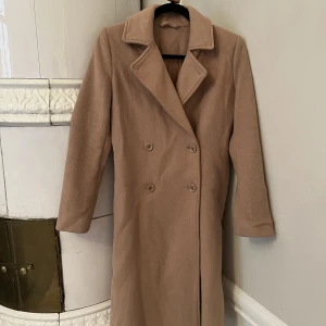 Ullkappa Samsoe Samsoe XXS - Ullkappa från Samsoe Samsoe. Lång och tight fit. Kommer med tillhörande skärp. Använt skick. Knäppning med knappar. Fickor på sidan. 