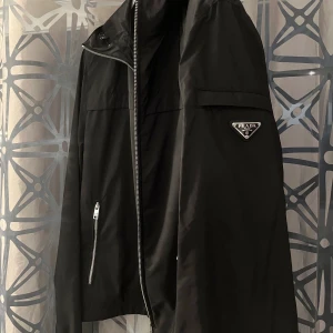 Prada - Vindjacka - Hej! Säljer en helt ny oanvänd Prada vindjacka i storlek L.  Fraktar i hela Sverige. Möts i Stockholm. Skick: 10/10. Mitt pris: 6 500 kr.