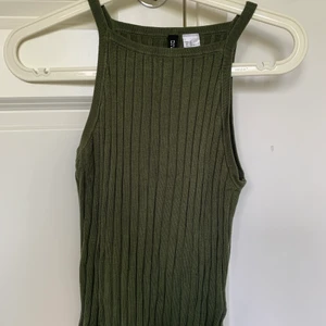 Ribbad khaki grönt linne - Ett stretchigt linne från H&M i storlek Xs men passar även S. Ribbat och typ halterneck. Använd endast ett fåtal gånger. Frakt tillkommer!
