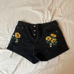 Snygga highwaist svarta shorts med broderade gula blommor.