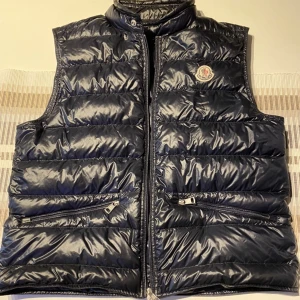 Moncler gui väst - Säljer min monclar gui väst. Mörkblå färg. Riktigt fint skick. Moncler-påse medföljer. Tunn så funkar även nu mot sommaren. Skriv vid intresse, säljs ändast till rätt pris🙌🏼mvh Edvin