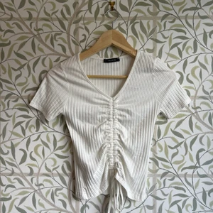 Vit T-shirt med åtdragbara snören - Smickrande vit, ribbad, t-shirt från Zalando som endast använts en gång. Plagget är i storlek S och du kan justera snöret precis som du vill. 