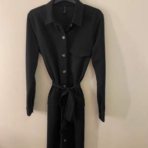 En svart lång skjortklänning med knyte i midjan.