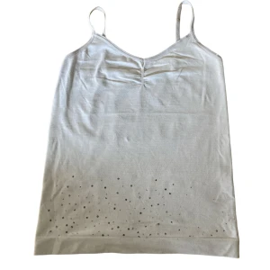 Vitt linne - Säljer mitt vita linne utan någon lapp, svarta prickar där det förut var stenar fast de åkt bort . Linnet är ungefär Xs men funkar för S 💕frakt tillkommer💕