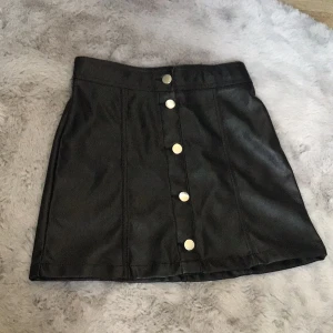  Svart skinnkjol i storlek 146 kommer från H&M  -  Den är använd fåtal gånger och går oss på något i midjan   