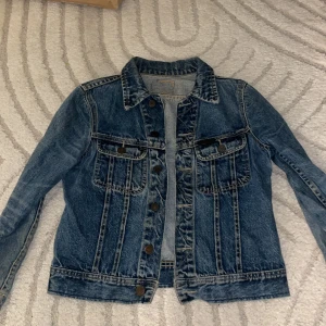 Klassisk blå jeansjacka - Snygg blå jeansjacka med klassisk passform och coola detaljer som bröstfickor med knappar och markerade sömmar. 