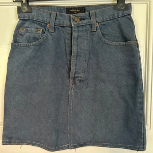 Blå jeanskjol från Valentino - Snygg blå jeanskjol från Valentino med klassisk femficksdesign och bälteshällor. Kjolen har en rak passform och rå kant nertill för en cool vibe. Perfekt att matcha med sneakers eller boots för en avslappnad look. Storleken står ej, men är ungefär i XS.💙