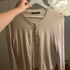 Beige kofta från 157 med knappar - Snygg beige kofta från 157 med rund halsringning och ribbade muddar. Koftan har knäppning framtill med matchande knappar och är långärmad. Perfekt att slänga över en topp för en chill och stilren look. Sparsamt använd och normal i storleken. Hör gärna av er vid frågor eller funderingar! 💕