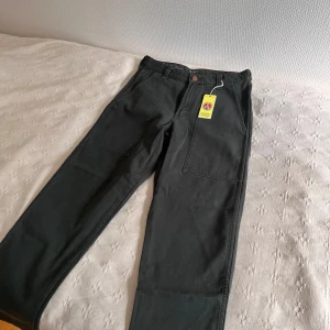 Wrangler Casey Pants utilitybyxor M - Säljer ett par mörkgröna Casey Pants från Wrangler i utility-stil. Byxorna har raka ben, stora utanpåfickor fram och bak samt bälteshällor. Tillverkade i bomull för en skön och slitstark känsla. Aldrig använda, för stora för mig och skickade aldrig tillbaks dom🥲