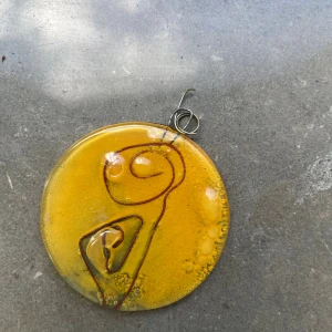 Unikt gult glashalsband med tråd - Runt halsbandshänge i glas med intensiv gul färg och abstrakt mönster av inbäddad röd metalltråd. Hänget har en handgjord känsla och cool konstnärlig vibe, perfekt för dig som gillar statement-smycken och vill sticka ut.