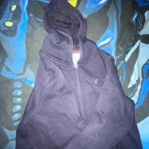 Mörkblå hoodie från GANT med dragkedja - Säljer en mörkblå hoodie från GANT med dragkedja framtill och klassisk huva. Tröjan har broderad GANT-logga på bröstet och är tillverkad i mjuk bomull. Perfekt för dig som gillar stilrena och bekväma plagg med sportig känsla.❤️🫶🏼