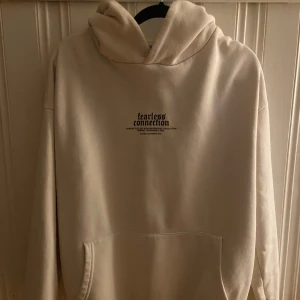 Beige hoodie  - Beige hoodie från new yorker med tryck på bröstet och stor grafisk print på ryggen med texten 'live without fear.' och en brinnande bil. Mjuk bomullskänsla, stor huva och känguruficka framtill. Perfekt för dig som gillar streetwear vibes. Storlek XS men passar S också! 