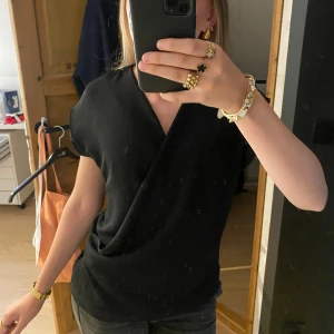 Svart omlottopp  - Svart omlottopp med korta ärmar och v-ringning! Pris kan diskuteras!💕