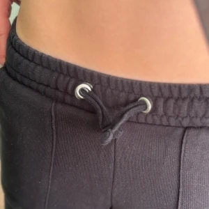 Svarta mjukisbyxor med snörning - Svarta mjukisbyxor med raka ben, resår i midjan och snörning framtill. Byxorna har stora fickor både fram och bak och är gjorda i mjukt bomullsmaterial. Perfekta för chill dagar eller när du vill vara bekväm men ändå se snygg ut.