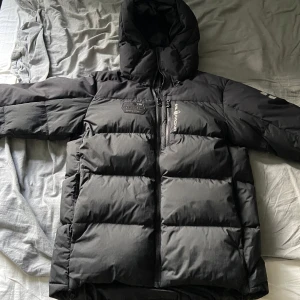 Svart pufferjacka från Sail Racing - Säljer en svart dunjacka från Sail Racing i storlek medium. Perfekt för kalla vinterdagar då den håller värmen väldigt bra. Säljer pågrund utav att den inte används längre.