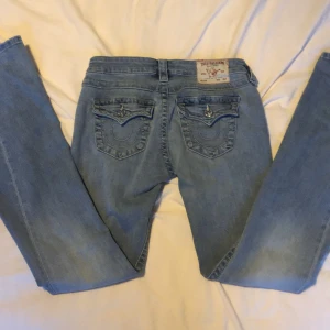 True Religion Joey Low Rise Flare Jeans - Snygga ljusblå jeans från True Religion, modell Joey Low Rise Flare. Storlek 25. Nästan oanvända, andvänt 5 gånger. Dom har två små hål på insidan om man vill ha dom tightare så sätta i ett snöre, kolla bild fyra. (Man kan sy igen de) 🩵