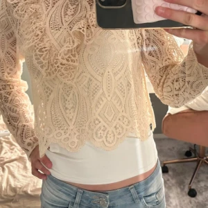 Beige blus  - Superfin beige blus i spets med långärmad design och högt halsringning. Blusen har snygga volangdetaljer framtill. Från Zara i strl xs 