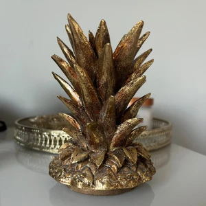 Guldig ananas - Det är egentligen ett lock till en vas (har inte kvar) men jag har använt den som dekoration på en hylla. Jättefin