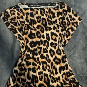 Leopardmönstrad topp  - Cool topp från lager 157 med leopardmönster i beige, svart och bruna toner. Modellen har korta ärmar och en figurnära passform. Använd ett fåtal gånger!