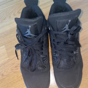 Jordan black cats 4 s - Säljer ett par svarta Nike Air Jordan 4 sneakers med klassisk Jumpman-logga på plösen och hälen. Skorna har snörning, meshpaneler och detaljer i syntet och mocka. Den robusta sulan och den ikoniska designen gör dem till ett måste för dig som gillar streetwear.