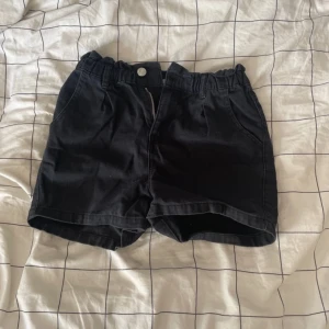 Svarta shorts från 157 med dragkedja - Svarta shorts från 157 med elastisk hög midja, dragkedja och knapp framtill. Modellen har två fickor fram och två bak, tillverkade i mjuk bomull. Perfekta för chill dagar och har en loose passform som ger skön vibe.