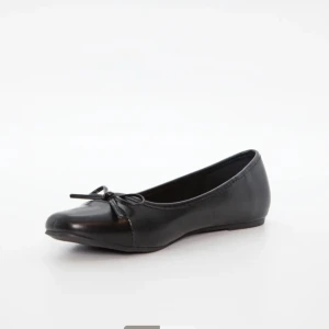 Svarta ballerinaskor med rosett - Klassiska svarta ballerinaskor i skinnimitation med rund tå och en söt rosettdetalj framtill. Skorna har platt sula och enkel design som passar till många olika outfits. Perfekta för dig som gillar stilrena och tidlösa skor.