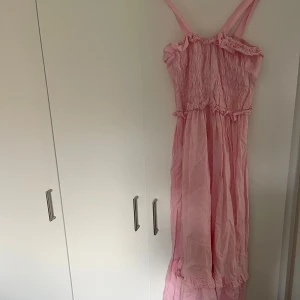 Ljusrosa långklänning från Esmée - Säljer en drömmig ljusrosa långklänning från Esmée med smock upptill, volangdetaljer och tunna axelband. Klänningen har en flowy passform💕💕💕