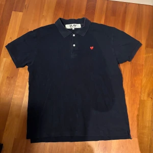 Svart polo piké Comme des Garçons - Svart polo t-shirt från Comme des Garçons PLAY. Storleken är XL men passar mer som L.