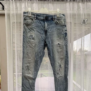Blå slitna jeans från FSBN - Säljer ett par blå jeans från FSBN med schyssta slitningar och hål för en riktigt avslappnad vibe. Jeansen har klassisk femficksdesign och normal passform. Perfekta för dig som gillar en lite ruffare streetstil.