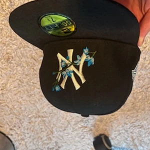 Svart New Era keps med blå blommor - Säljer denna svarta med blå sällsynt design new era keps, den kommer inte till nå användning därför säljs den, kanppt använd, inte ett ända flöde.