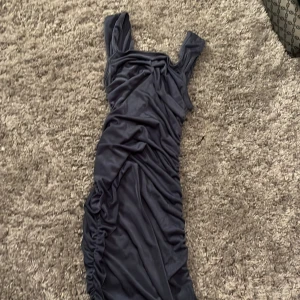 Mörkblå kortklänning - Supersnygg mörkblå kortklänning med rynkade detaljer längs sidorna. Klänningen har breda axelband och en tight passform som framhäver figuren. Knappt använd 